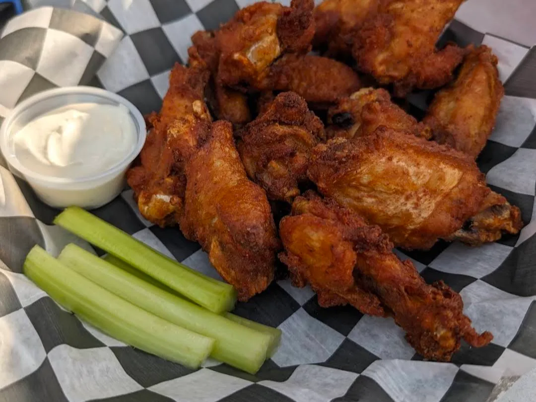 A basket of crispy fried chicken wings with celery and dressing — a Frogtown favorite